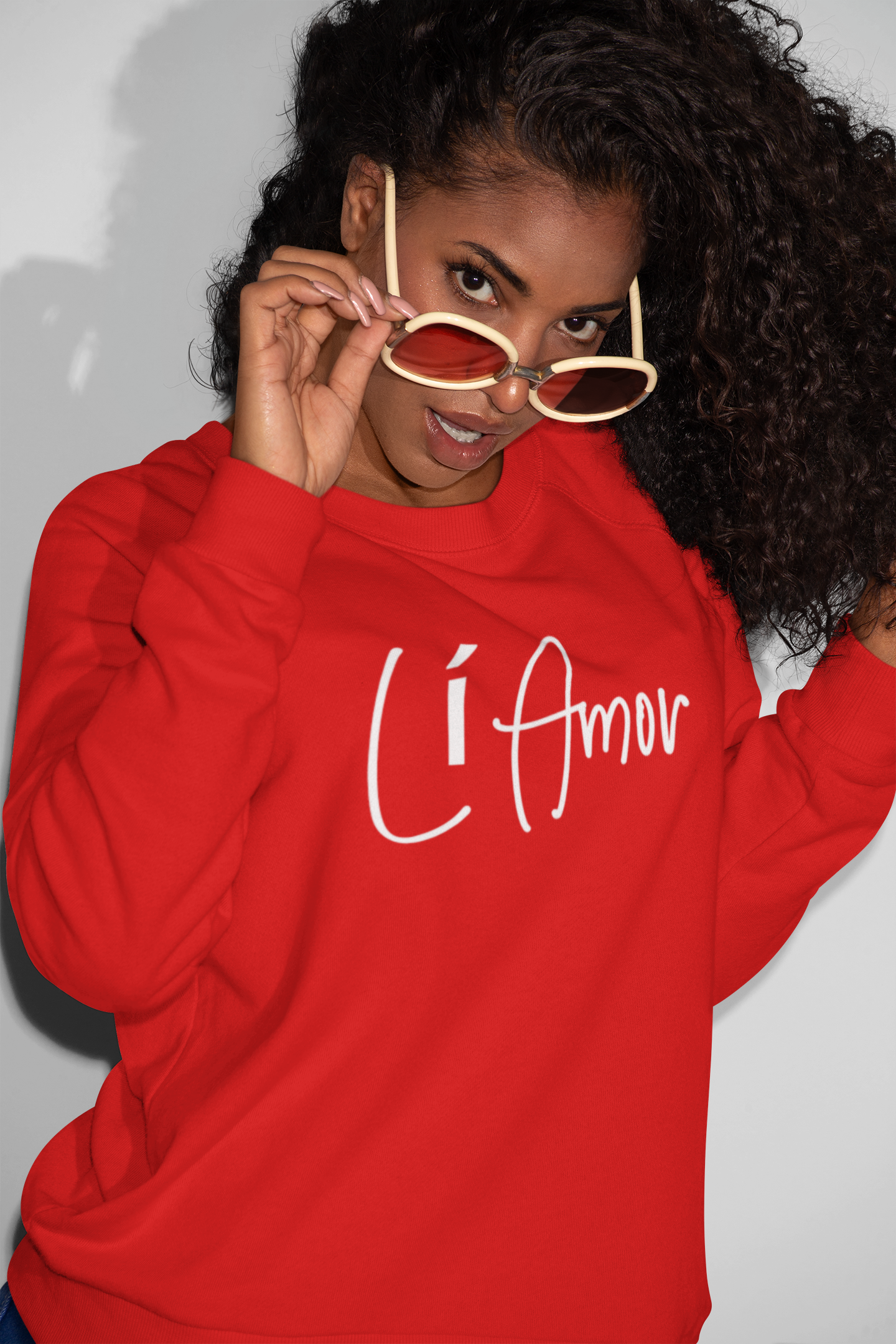 Woman wearing a red Li Amor crewneck sweatshirt with the white Li Amor logo across the chest.